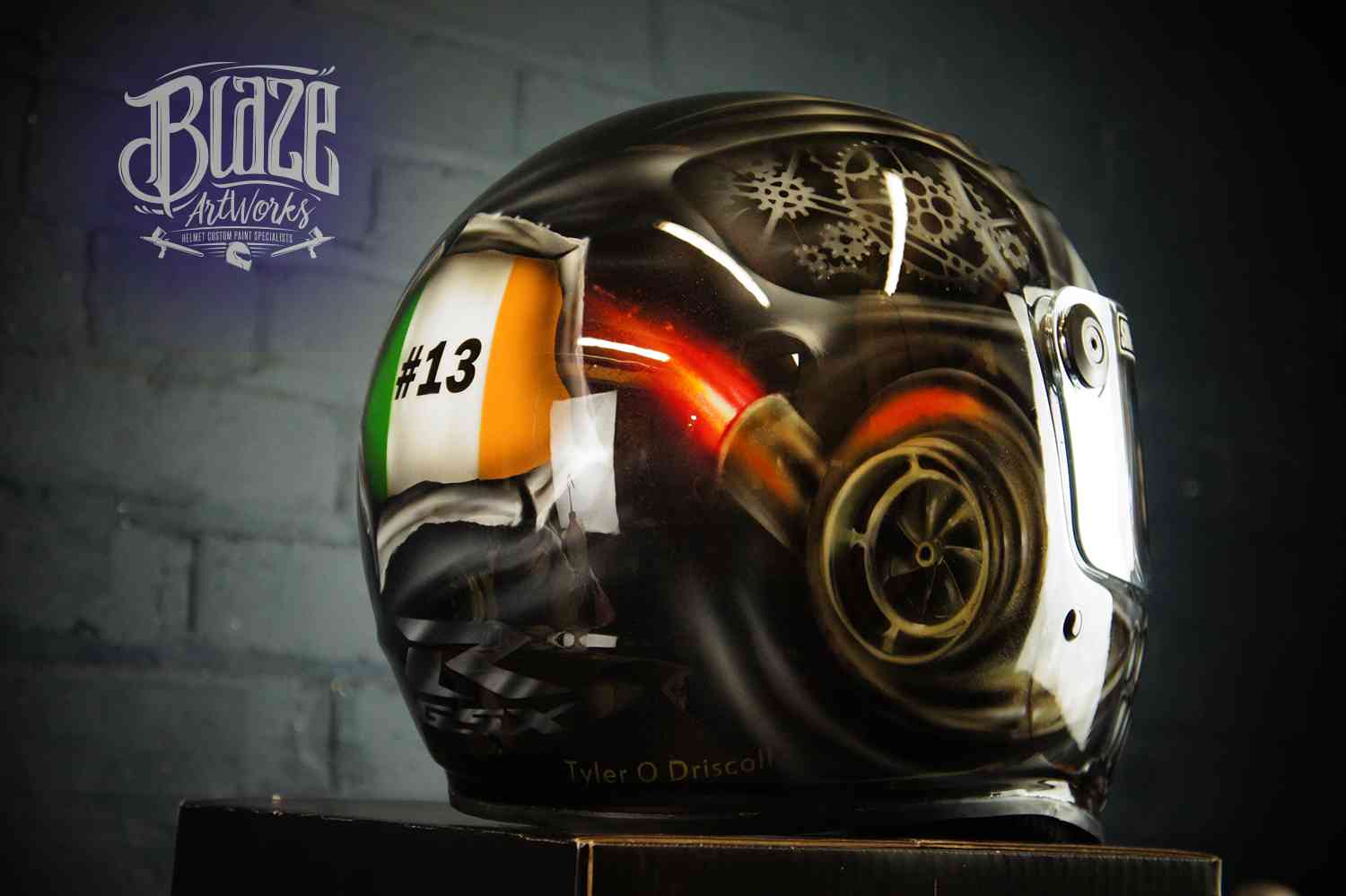 Black motorcycle helmet with airbrushed steampunk skull design featuring golden mechanical gears, orange turbo charger, and Irish flag